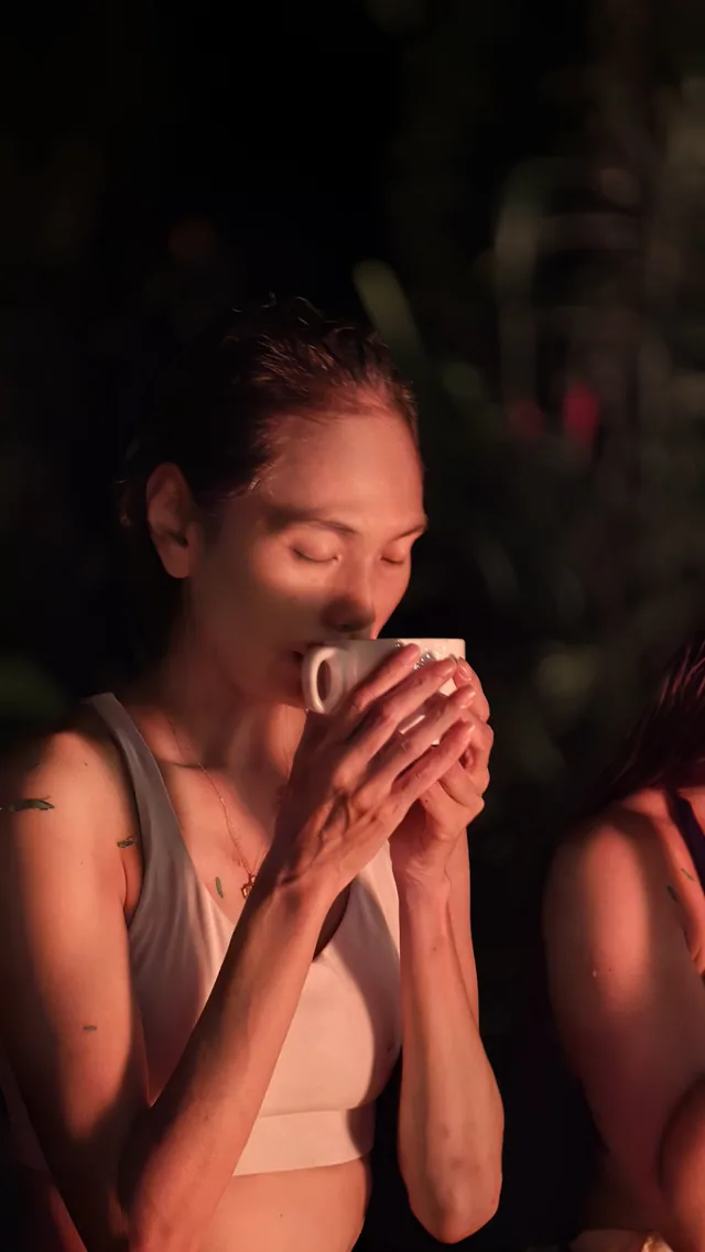A woman holding a cup at an evening gathering