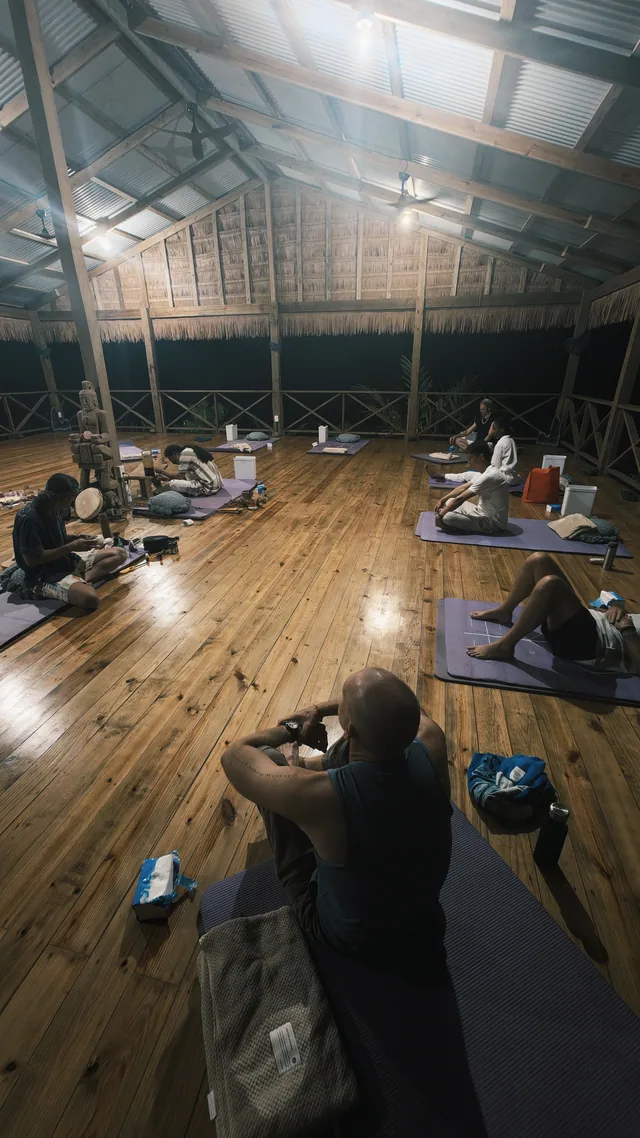 People seated apart on mats during an evening ceremony