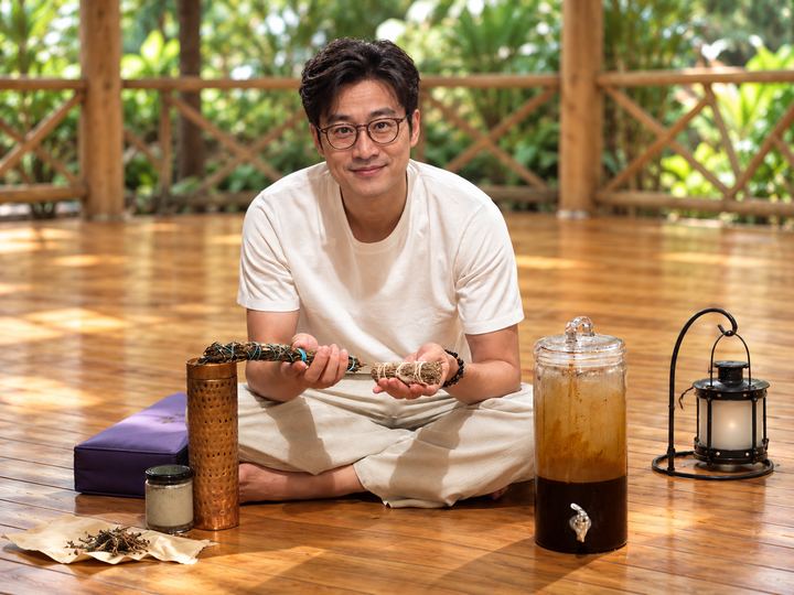 Illustrative portrait of a participant holding herbs in a warm pavilion